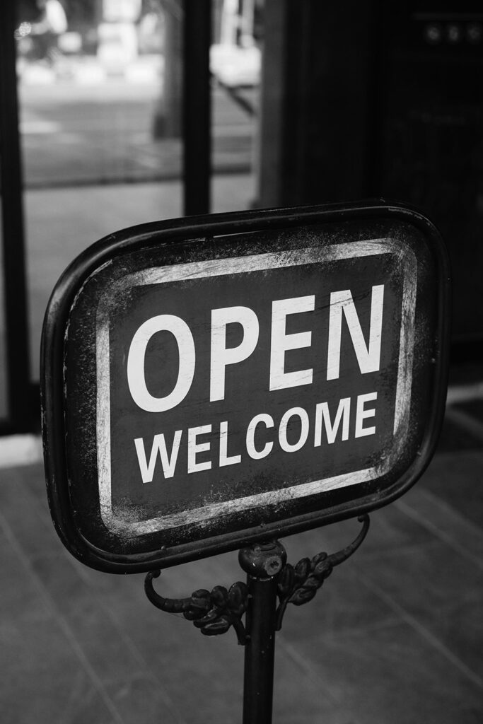 Black and white image of a sign that says "Open" and "Welcome"